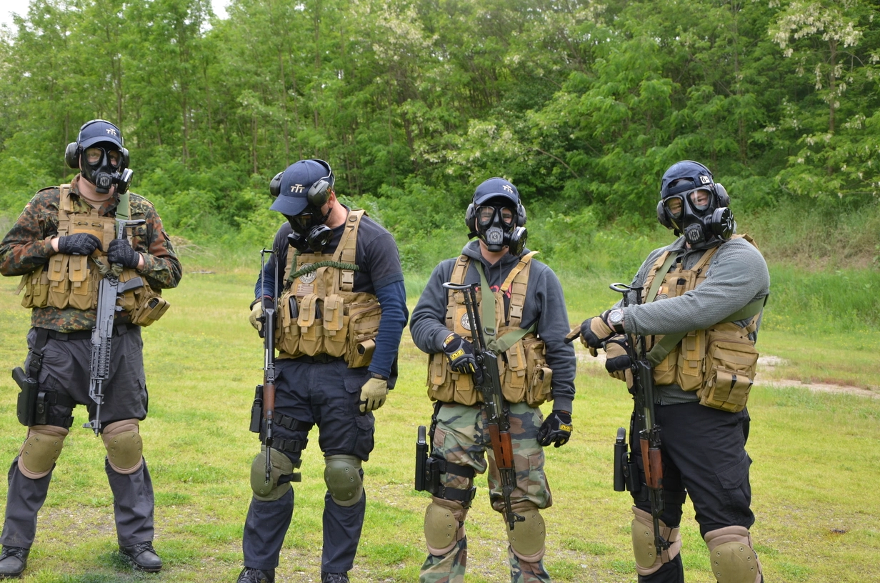 Ljudi stoje sa puskama i gas maskama